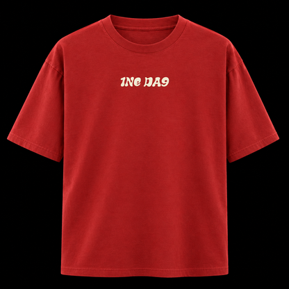 A red short-sleeve crewneck t-shirt with the text '1NE DA9' printed in a cream-colored retro font on the chest, displayed against a solid black background.